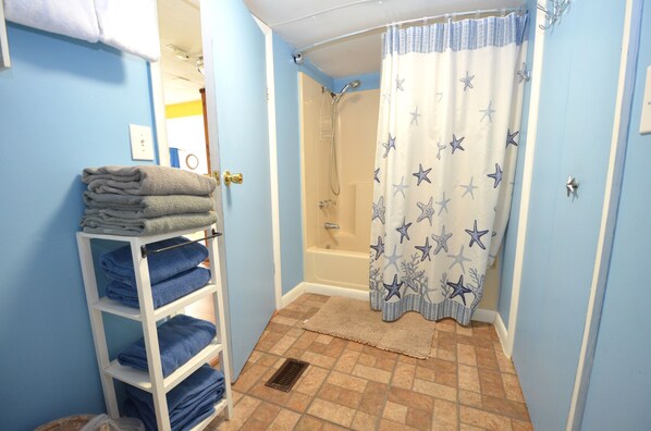 A bathroom with a shower, a towel rack with folded towels, and a star-patterned shower curtain.