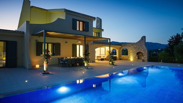 Una casa moderna de dos pisos con piscina, mobiliario exterior y arquitectura de piedra.