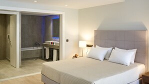 Una habitación de hotel moderna con una cama grande, ducha integrada y baño pequeño.