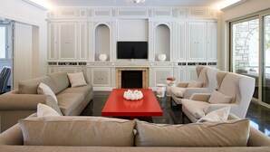 Una sala de estar con chimenea, televisor y una mesa de centro roja.