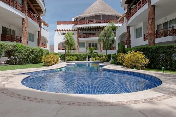 Un complexe hôtelier doté d’une piscine centrale, de nombreux balcons et d’un aménagement paysager de style tropical.