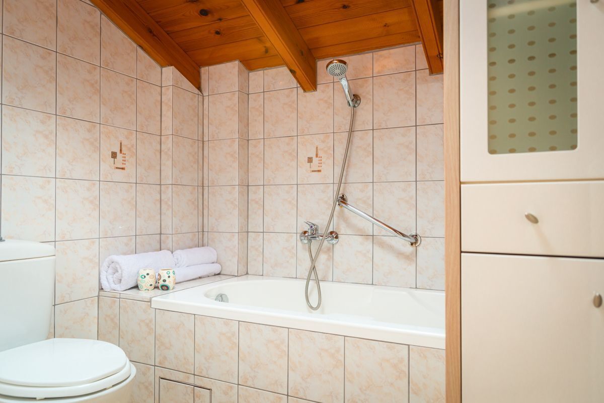 A bathroom with a bathtub, toilet, and tiled walls.