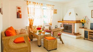 A cozy living room with wicker furniture, a fireplace, and a television. - Villa Mellow - Three Bedroom Villa, Sleeps 6 (Ionian Islands)