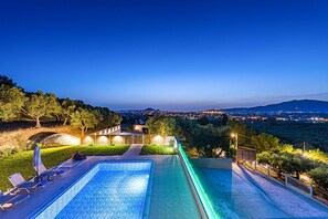 A swimming pool with lounge chairs and a view of a cityscape at dusk. - Villa Sarakina - Two Bedroom Villa, Sleeps 6 (Koridallos)
