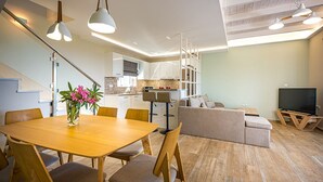 Een moderne woonkamer met een houten eettafel, stoelen, een bank en een televisie.
