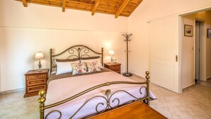 Une chambre à coucher avec un plafond en bois, un lit avec un cadre en métal, deux tables de chevet avec des lampes et une porte blanche.