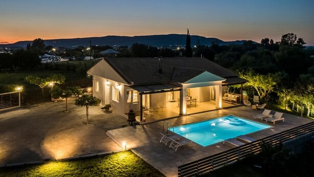 Une maison moderne dotée d’une piscine, d’un espace salon extérieur et d’un patio couvert.