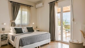 Une chambre avec un lit, des tables de chevet, un appareil de climatisation, une porte-fenêtre coulissante donnant sur un espace extérieur et une vue sur le paysage.