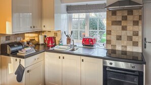 A modern kitchen with white cabinets, a black countertop, a red toaster, and a window with a view of greenery.