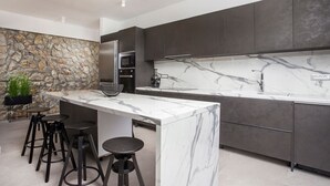 Una cocina moderna con encimera de mármol, armarios oscuros y una pared de acento de piedra.