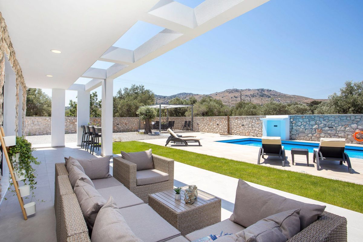 Un espacio al aire libre cubierto con piscina, muebles de mimbre y una pared de piedra.