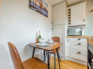 A compact kitchen with white cabinets, a microwave, and a dining area with a table set for two.