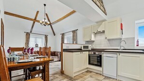 A kitchen with a dining area, wooden beams, a chandelier, and basic appliances. - 2 bedroom accommodation in South Barrow, near Yeovil (South Barrow, near Yeovil)
