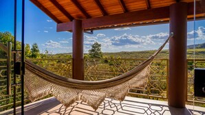 Eine Hängematte unter einer Holzpergola mit Blick auf eine üppige Landschaft.