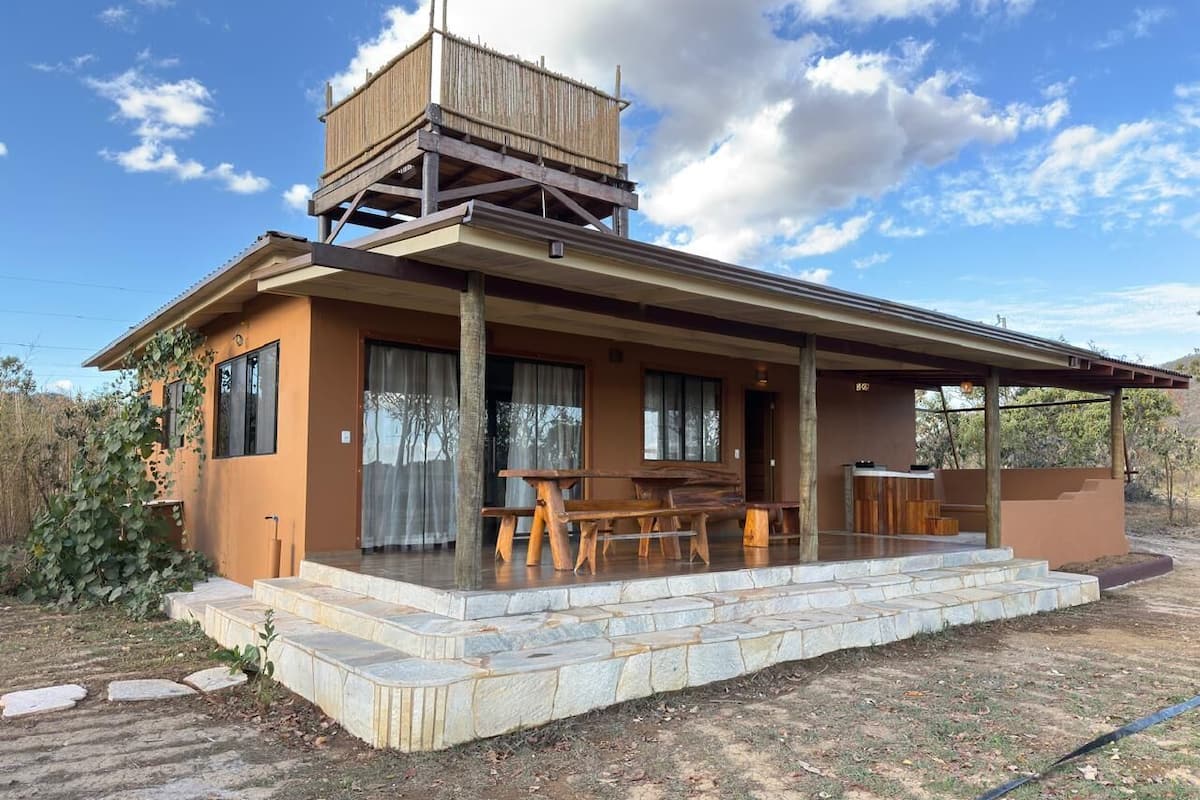 Ein modernes Haus mit überdachter Terrasse, einer Holzterrasse und einem steinbelagten Weg zum Eingang.