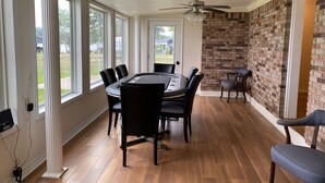 Un espace repas avec un mur en briques, un ventilateur de plafond et de grandes fenêtres.