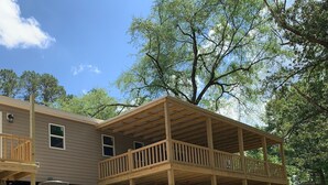 A two-story house with a wooden deck and a covered outdoor area.