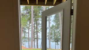 Une porte qui donne sur un paysage comprenant un lac, des arbres et une zone herbeuse.