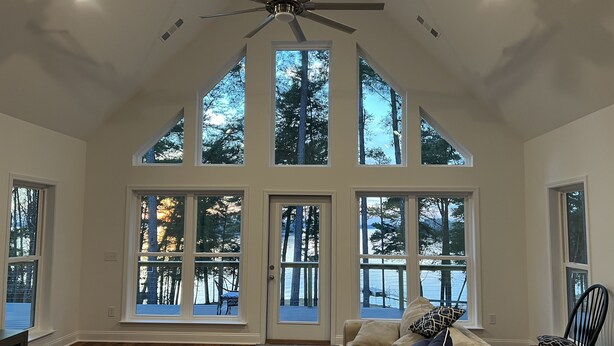 Un salon spacieux avec un plafond haut, de grandes fenêtres et un ventilateur de plafond.