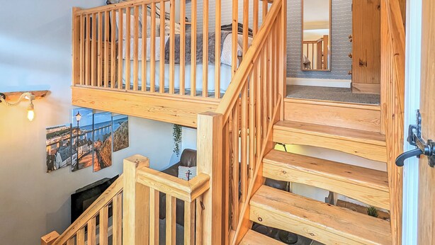 A wooden staircase with a railing, leading to a second-floor area with a view of the city. - The Hideaway Low Hawsker (Low Hawsker, near Whitby)