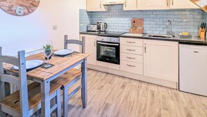 A kitchen with a wooden table, chairs, a toaster, a kettle, and a sink. - The Hideaway Low Hawsker (Low Hawsker, near Whitby)