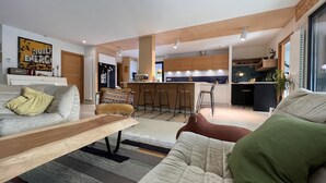 Una sala de estar moderna con un sofá, una mesa de centro y una cocina al fondo.