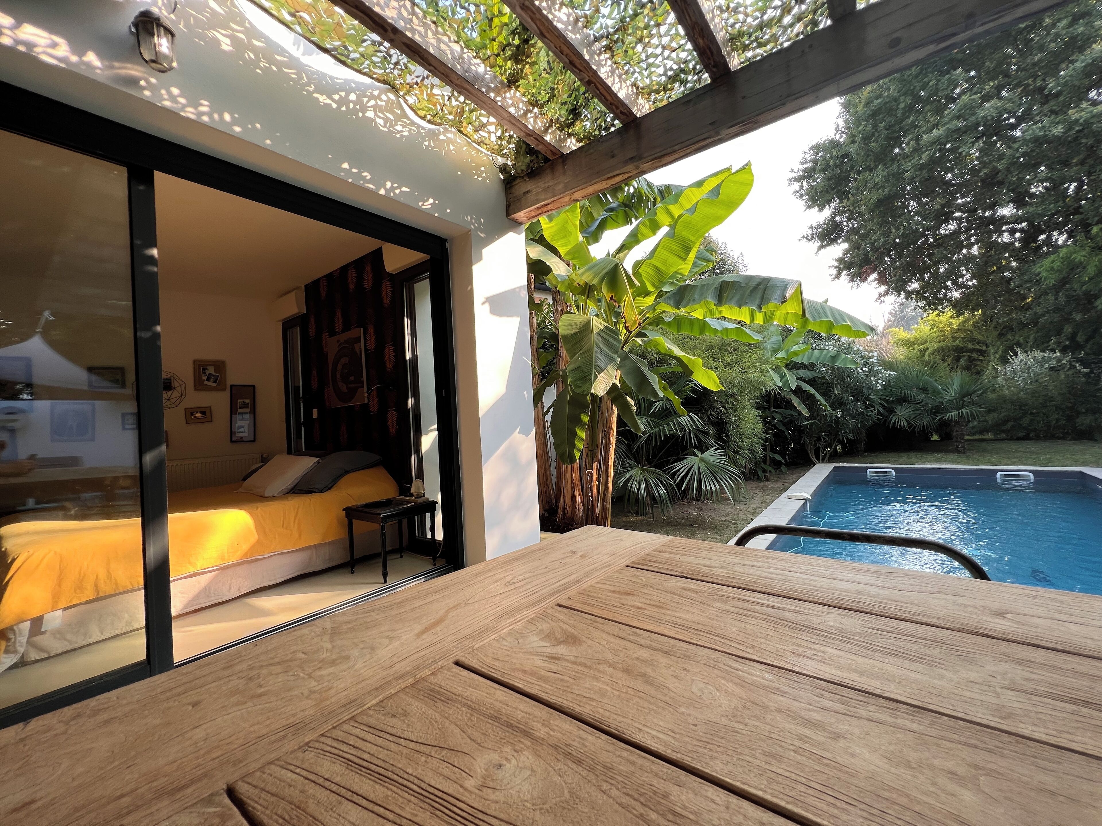 A bedroom with a bed, a small table, and a window overlooking a pool.