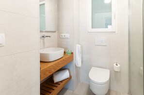 A modern bathroom with a white sink, wooden vanity, and a toilet.