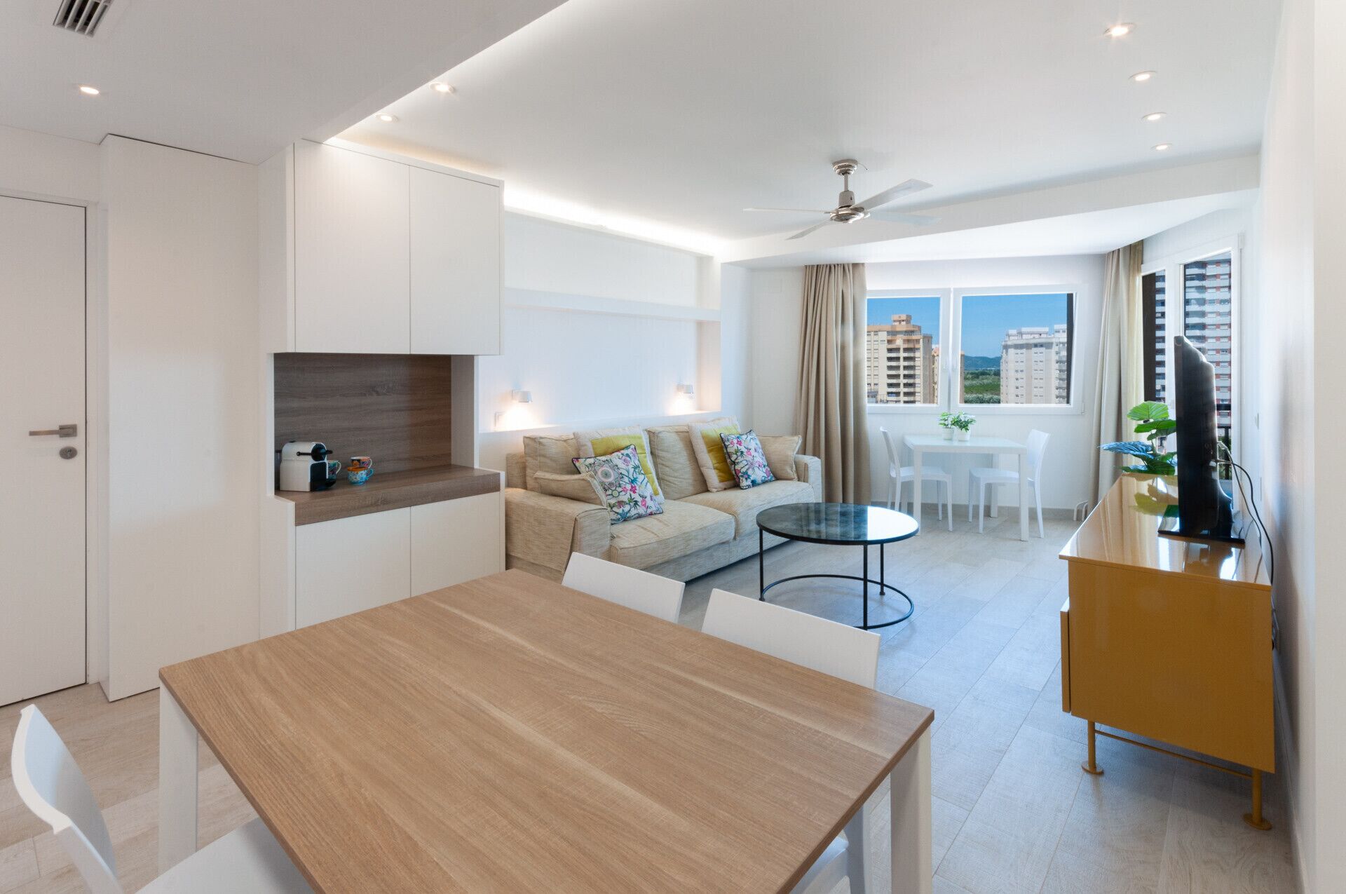Een modern appartement met een eethoek, een zithoek, een keuken met inbouwoven en een balkon met uitzicht op de stad.