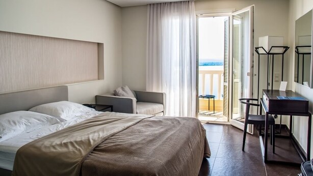A hotel room with a bed, a desk, a chair, and a view of the sea through an open door. - casa para viajeros de poco presupuesto (Quetzaltennago)