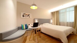 A modern hotel room with a curved bench, a bed, a small round table with a laptop, and a large window with curtains. - casa para viajeros de poco presupuesto (Quetzaltennago)