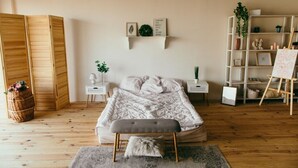 A bedroom with a bed, bedside tables, a bench, a shelf with decorative items, and a wardrobe. - casa para viajeros de poco presupuesto (Quetzaltennago)
