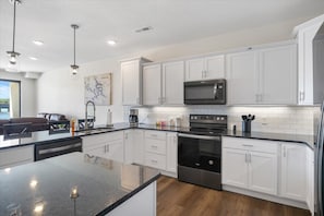 Features a large island with a granite countertop and stainless steel appliances.
