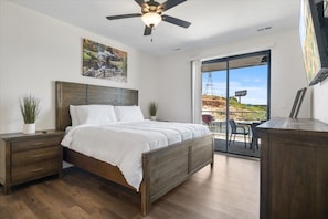 Relax in this serene bedroom with a large bed, nightstand, and dresser, and enjoy the view from the sliding glass door.