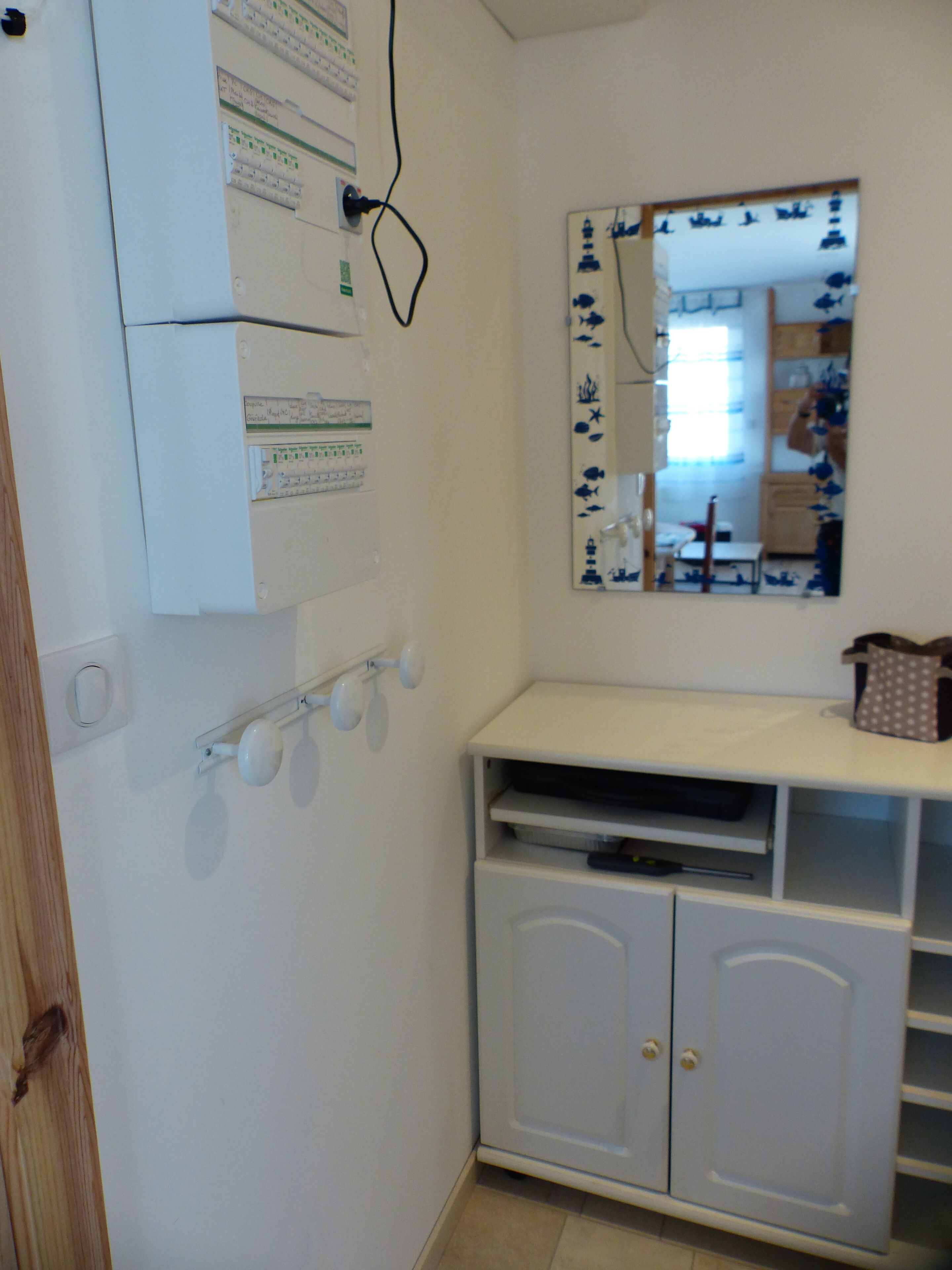 Ein kleines, weißes Badezimmer mit Spiegel, Schrank und Wandsteckdose.