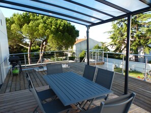 An outdoor patio with a table and chairs, surrounded by a metal railing and trees. - New Apartment (La Rochelle)