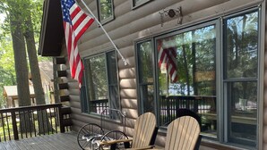 Eine Holzterrasse mit Adirondack-Stühlen und einer amerikanischen Flagge.