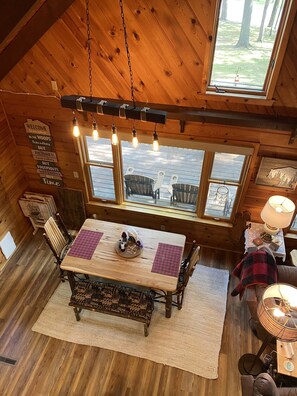 A cozy wooden cabin interior with a dining table, chairs, and a view of the outdoors.