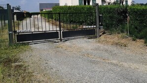 Una casa con camino de entrada de grava y una puerta de metal.