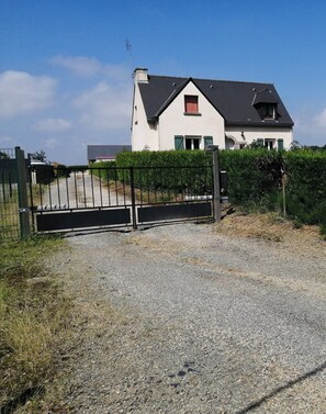 A house with a gravel driveway and a metal gate.