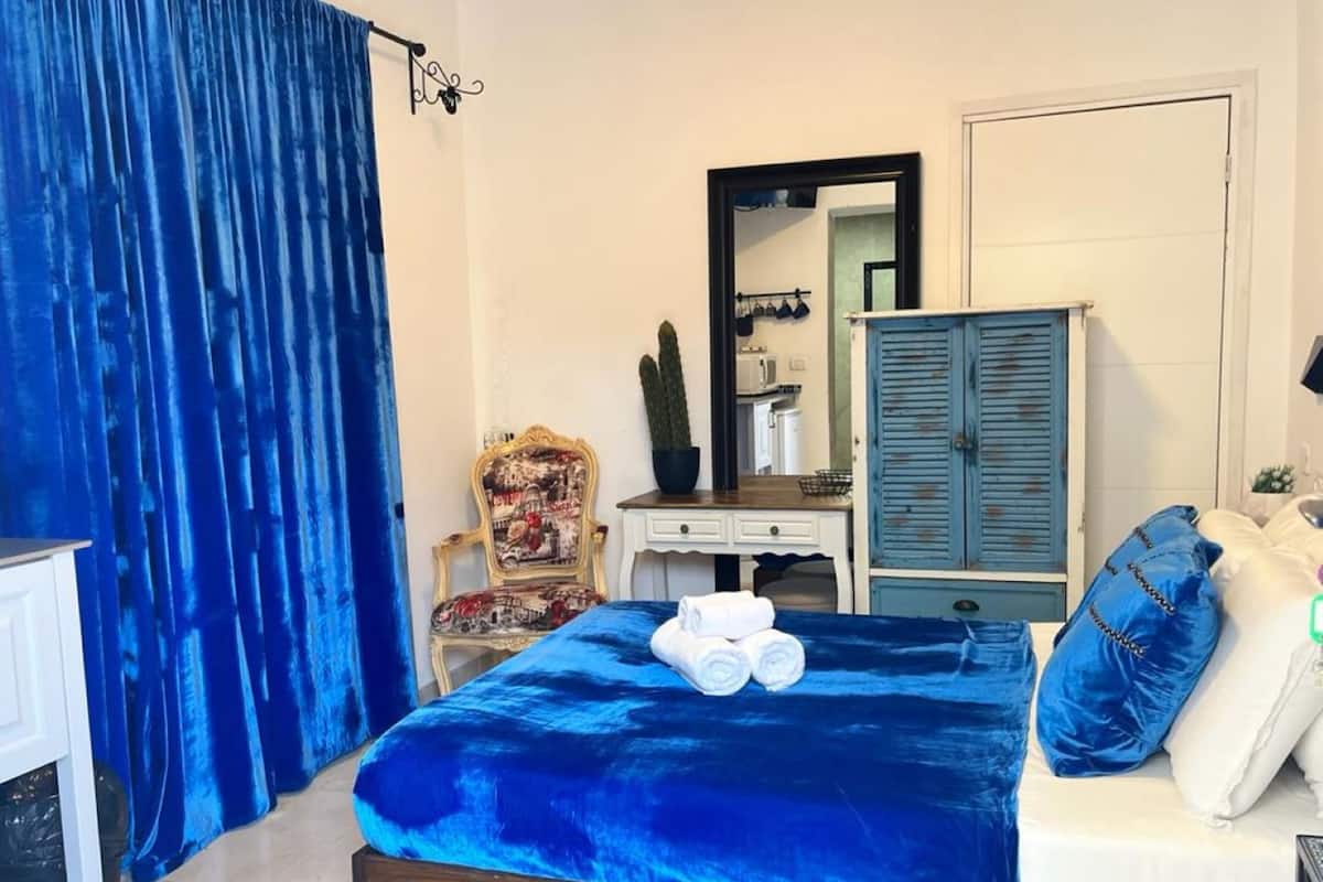 A bedroom with a large bed, a dresser, a chair, and a wardrobe.