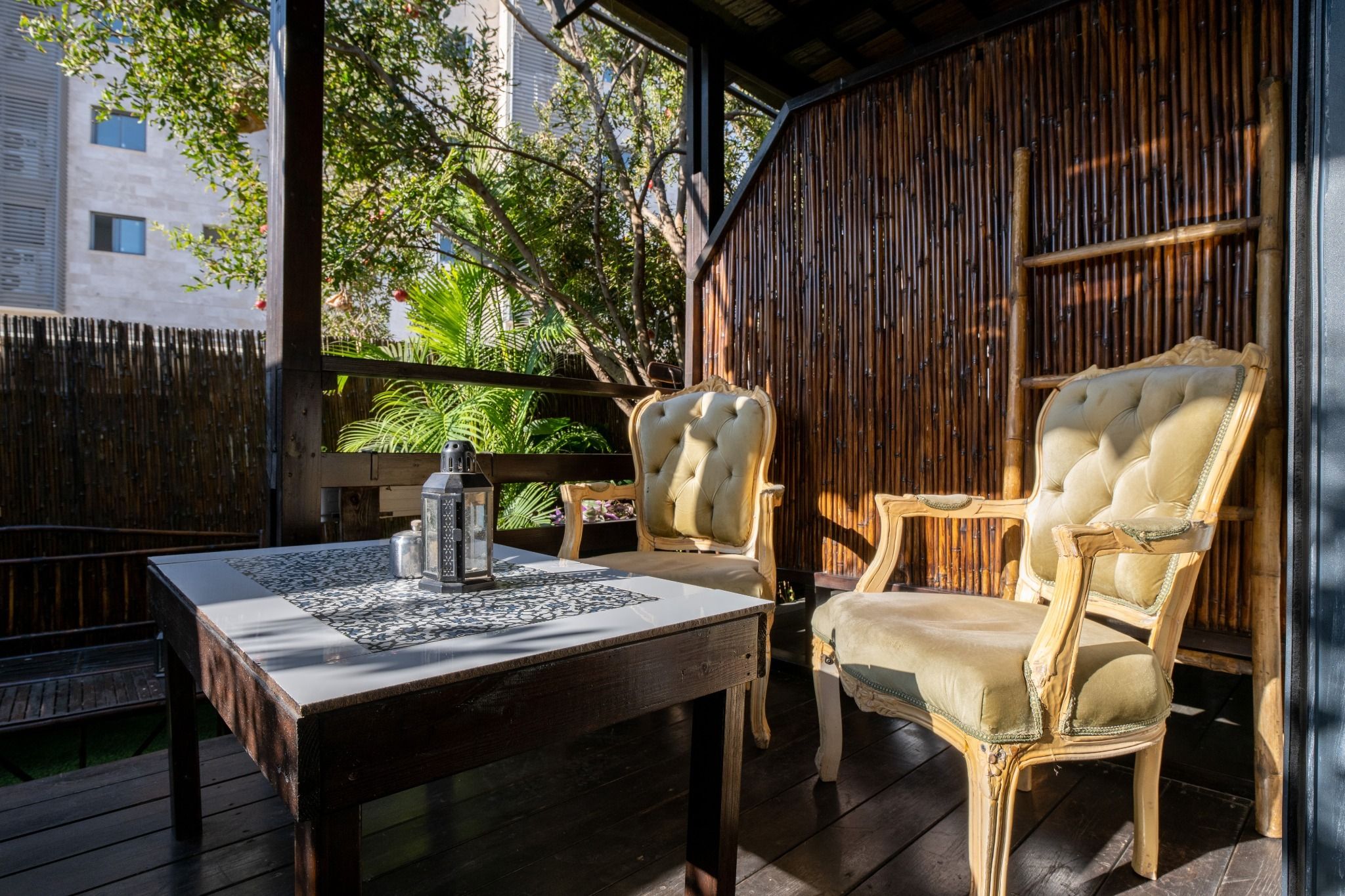 Un patio al aire libre con una mesa, dos sillas y un farol.