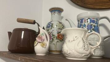 A shelf with a brown teapot, a white pitcher with floral designs, and a white teapot with a handle.