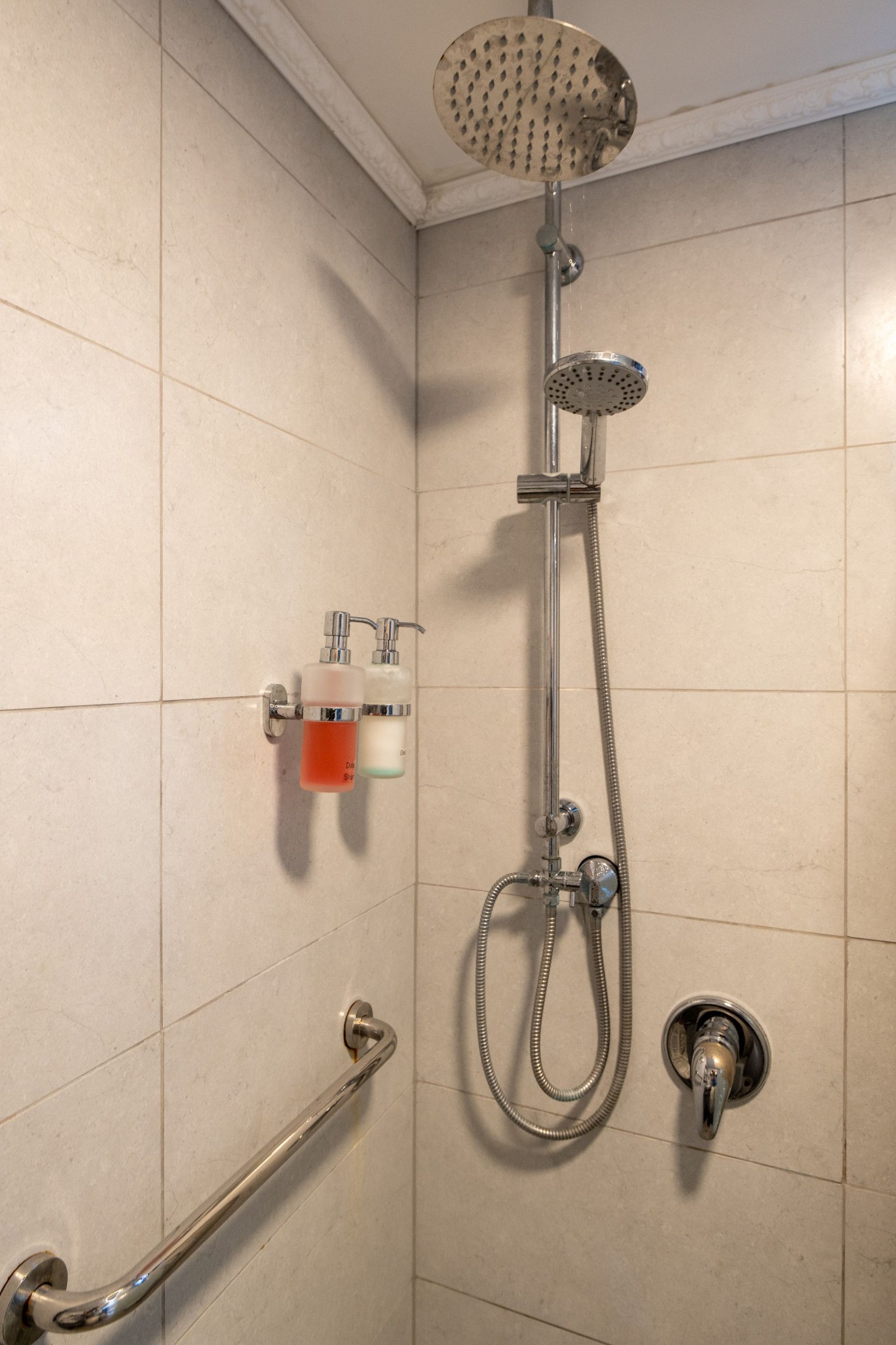 A shower with a handheld showerhead and a handheld hose.