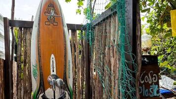 Uma prancha de surf encostada em uma cerca de madeira com piso de azulejos azuis em mosaico.