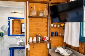 A wooden interior with a television, shelves with glassware, a sink, and a mirror. - Ahuzat Shaul Hotel Seaside (Hadera)