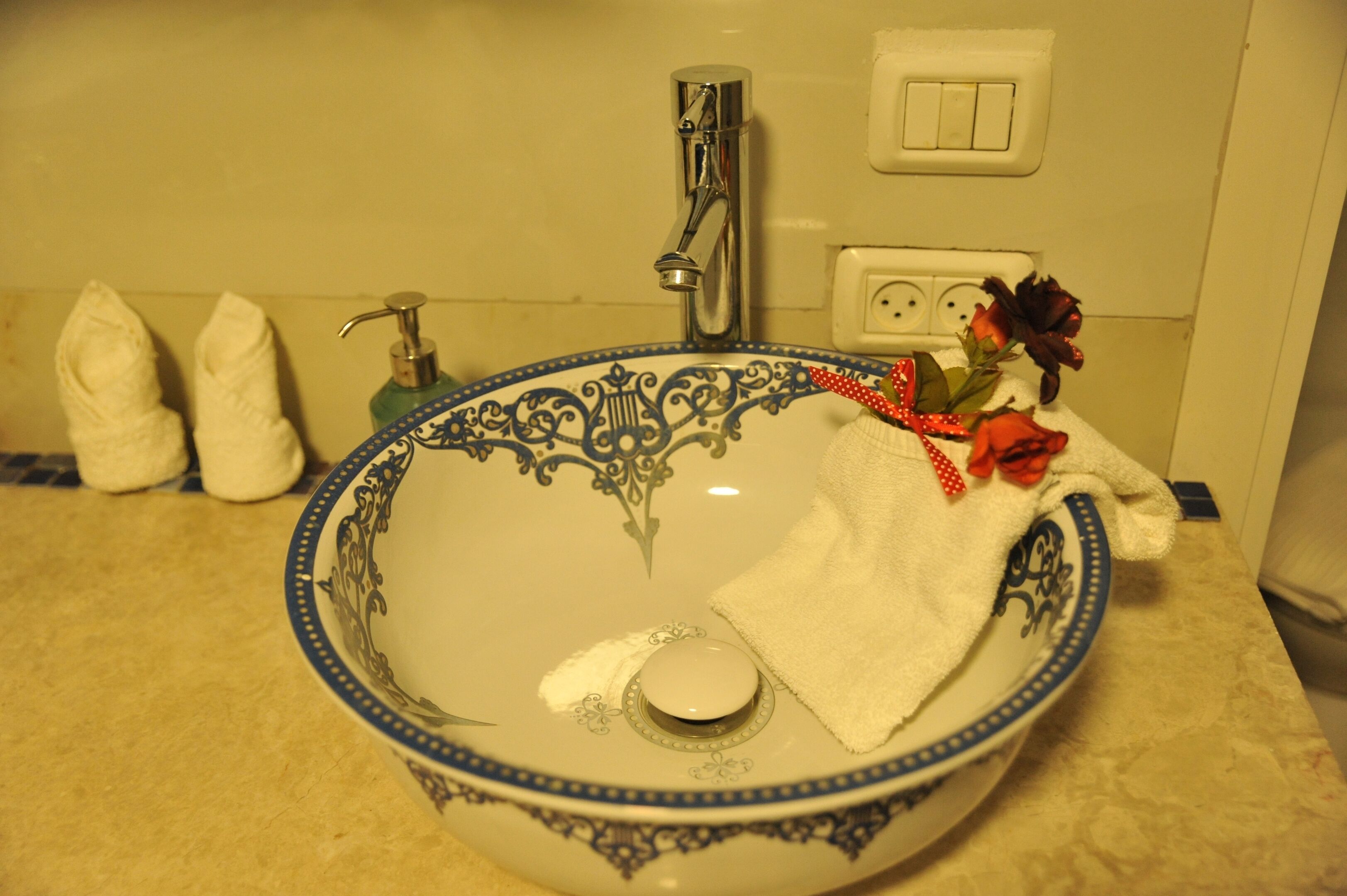 Uma pia de banheiro com uma bacia decorativa, uma torneira e uma toalha.