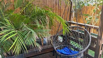 Eine Holzterrasse mit einem Korbstuhl und einem Blumentopf.
