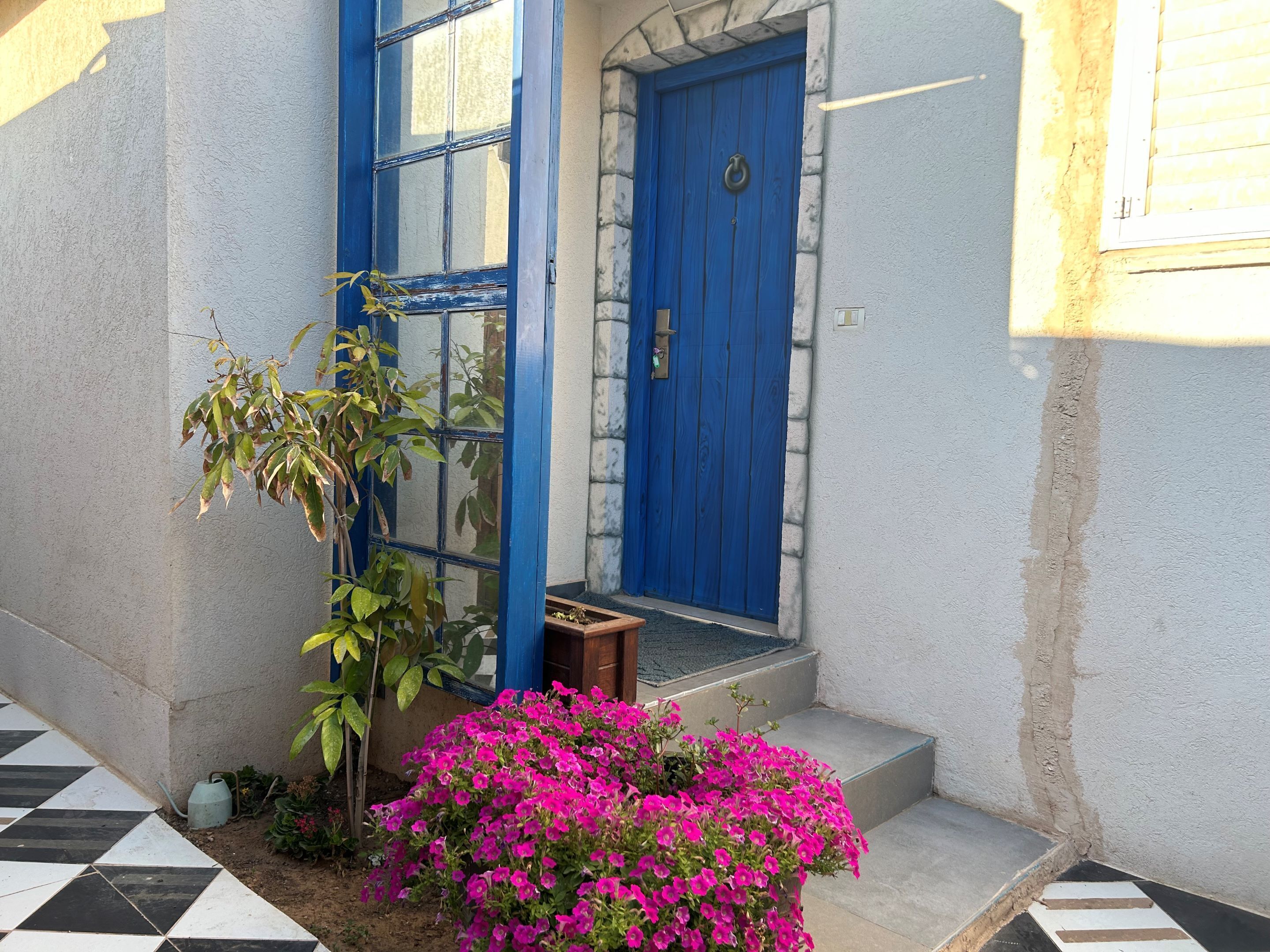 A blue door with a stone wall, a tiled entrance, and a small wooden bench.