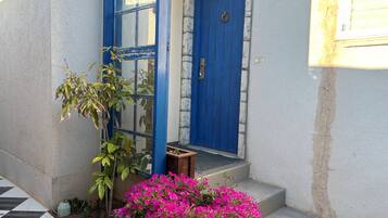 A blue door with a stone wall, a tiled entrance, and a small wooden bench.